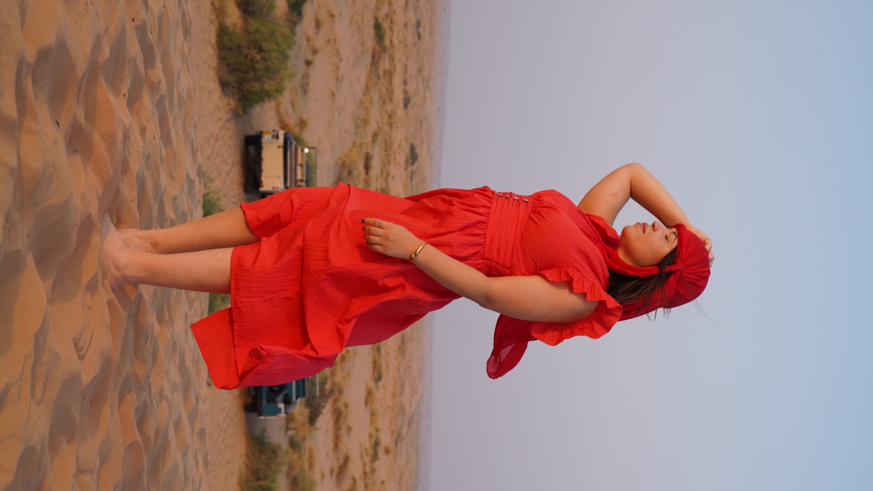 Giselle walking through desert dunes in a flowing red dress