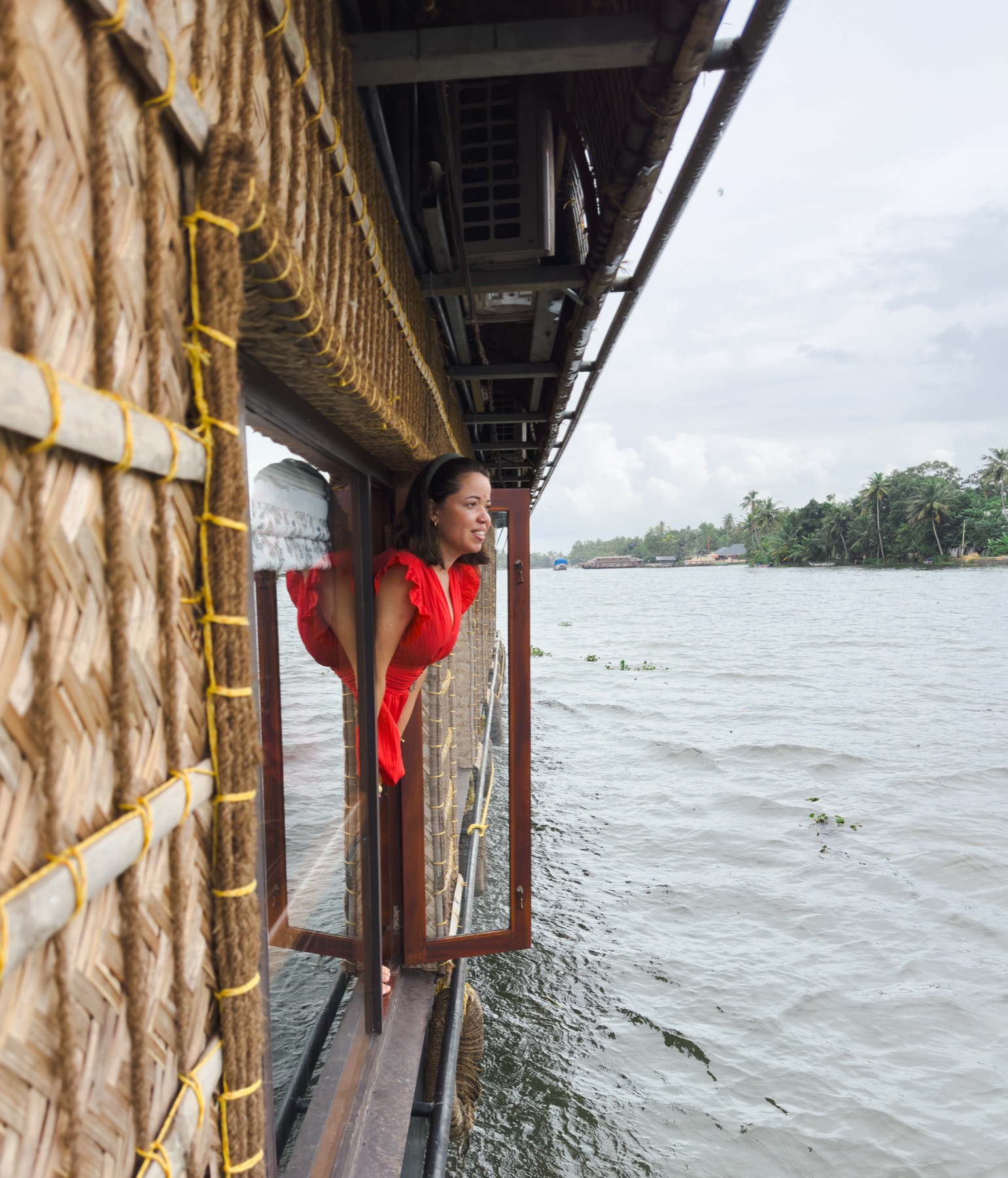 Giselle leaning from a houseboat window over tropical backwaters