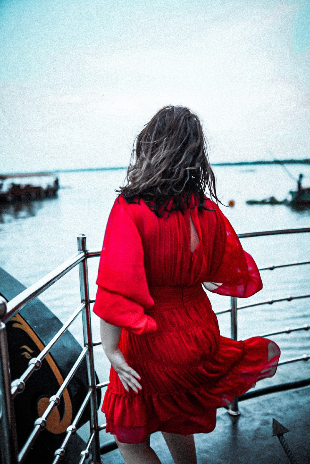 Giselle in a red dress aboard a boat at the water's edge