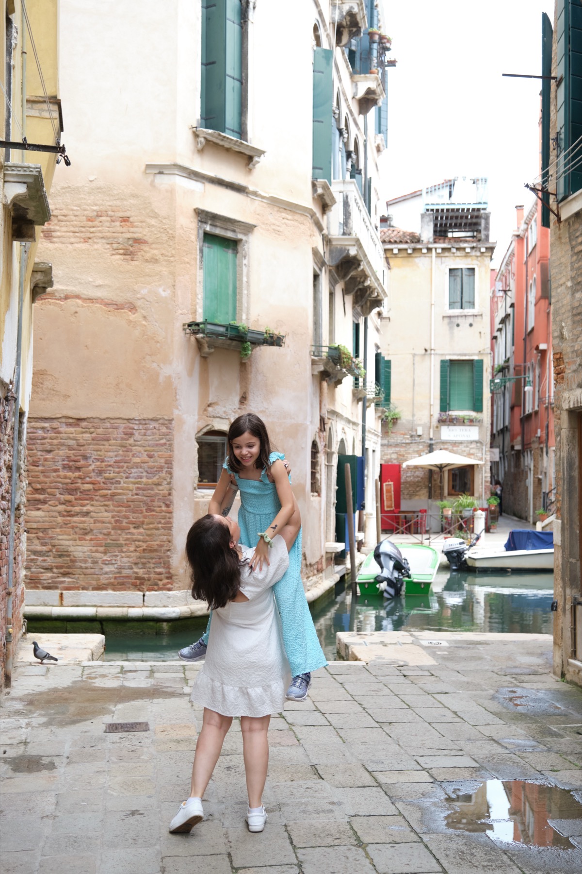 Giselle lifting her daughter in a quiet Venice canal alley